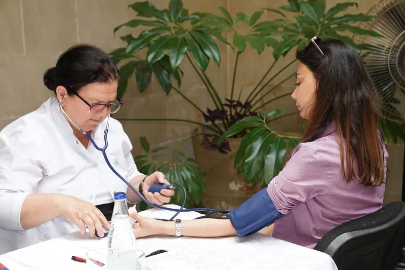 A nurse checking a resident's blood pressure at the bright front-desk table