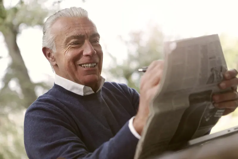 A resident laughing over the sports page on the front porch
