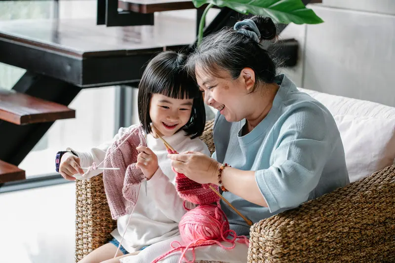 A resident teaching her granddaughter to knit during a Sunday visit