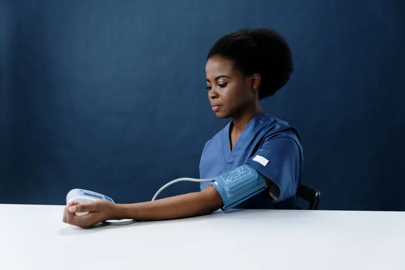 A nurse in blue scrubs taking a blood-pressure reading