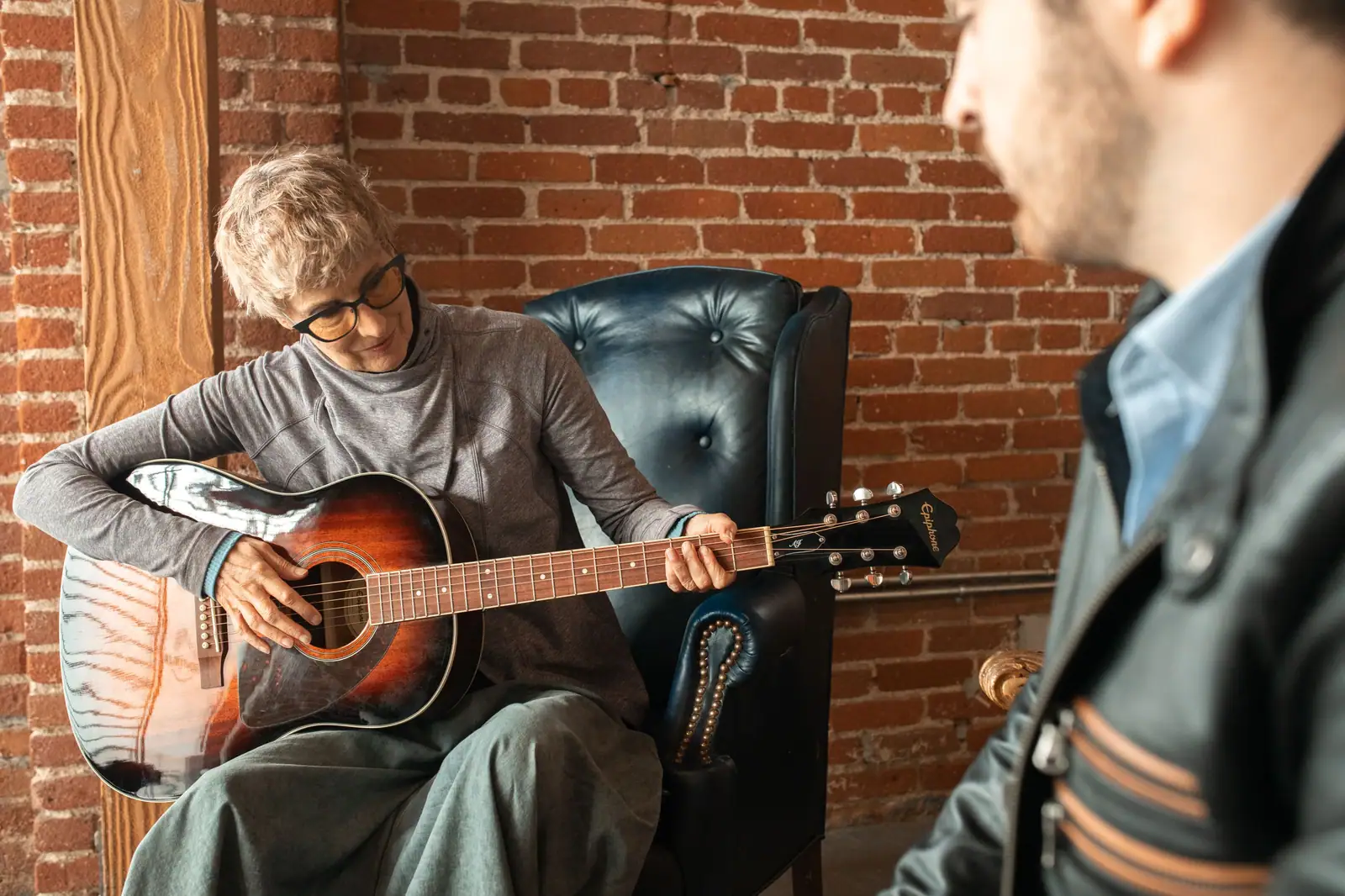 A resident playing guitar with the music therapist in the lounge