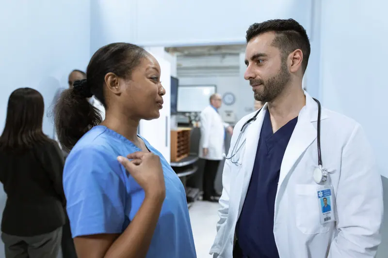 A nurse and a doctor talking at the nurses' station