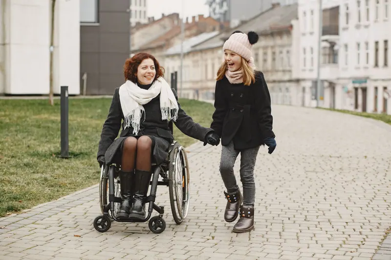 A rehab patient in a wheelchair out on the courtyard path with her granddaughter