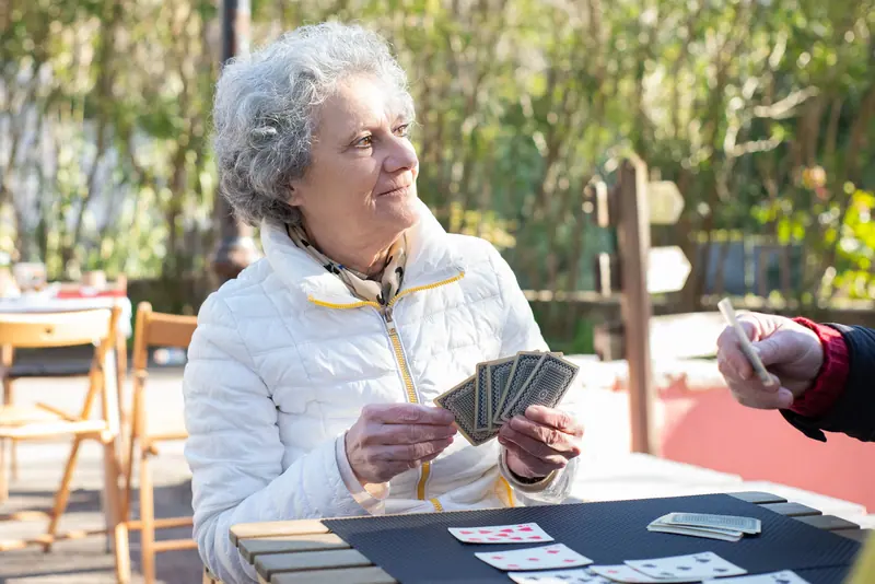 A resident holding a winning hand at the outdoor card table