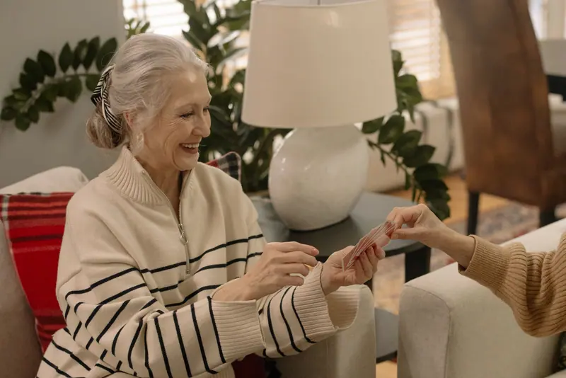 A resident smiling as she deals the cards in the dayroom
