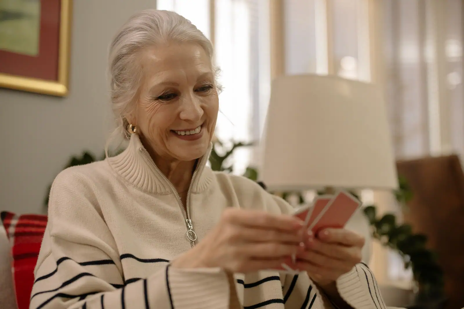 A resident in a striped sweater laughing over a hand of cards in the parlor
