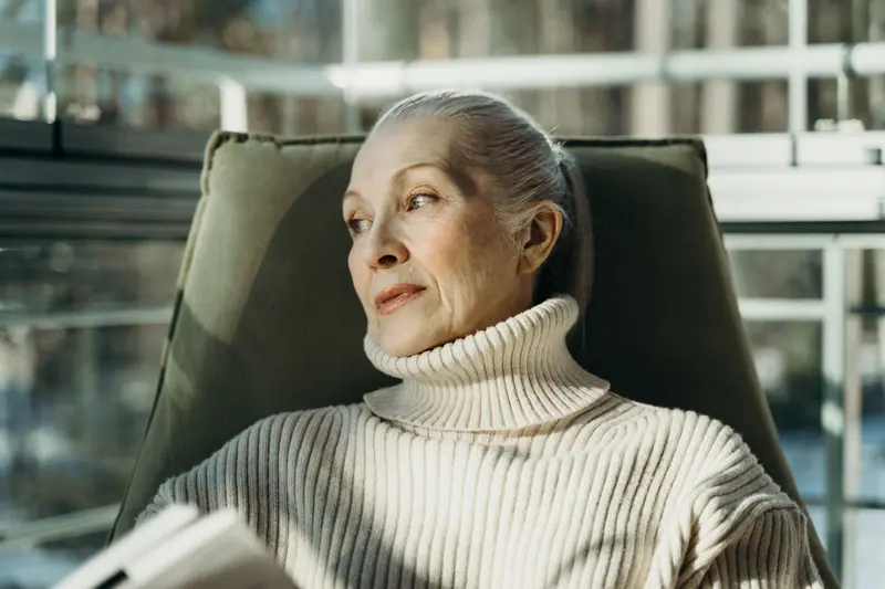 A resident resting in a chair by the sunroom windows