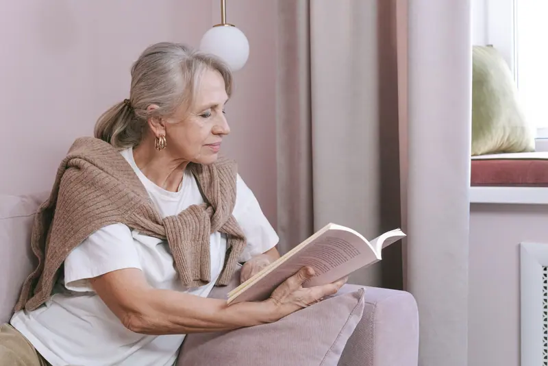 A resident reading in a pink armchair