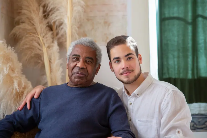 A resident with his arm around his grandson on a visit