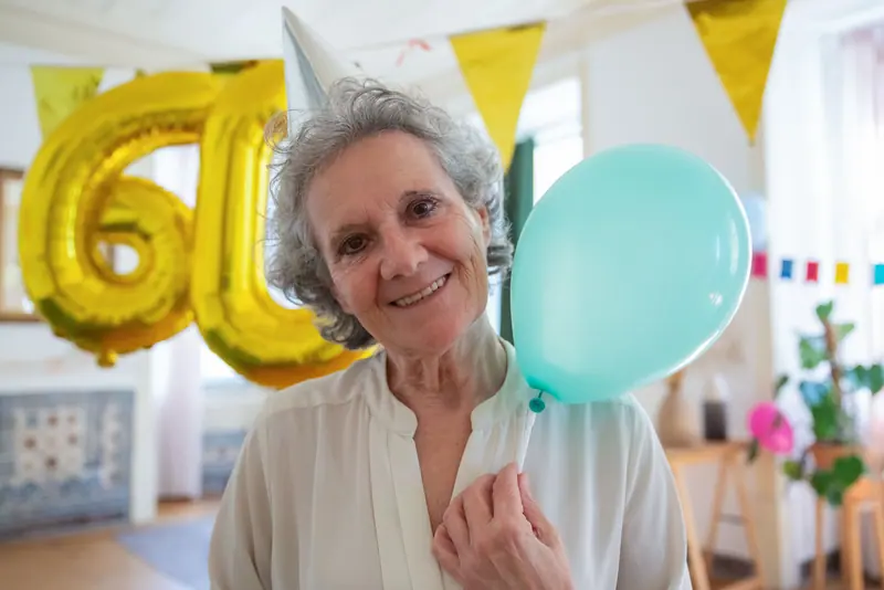 A resident holding a balloon at her birthday party