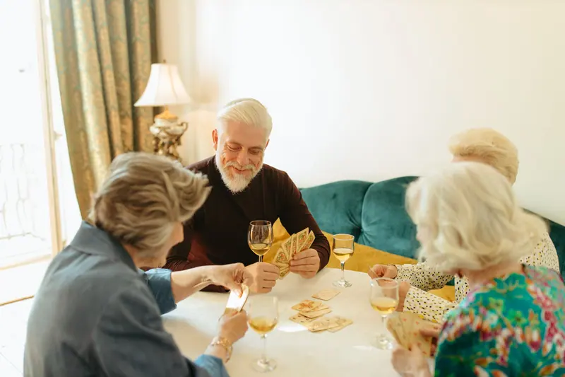 Residents playing cards at a round table in the afternoon light