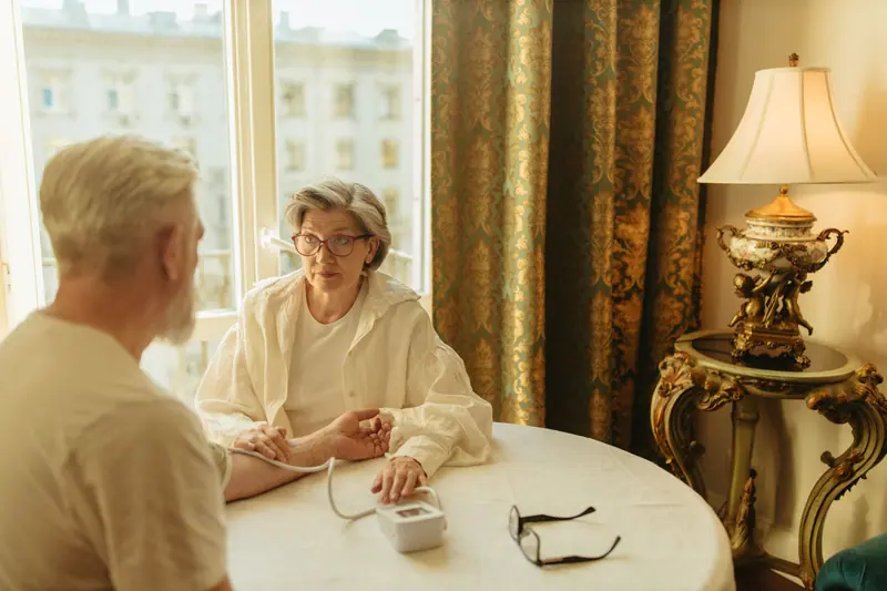 A resident and her husband at a table by the lamp