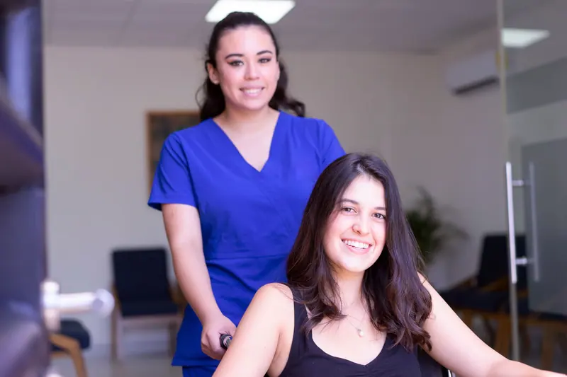 A nurse aide smiling with a resident in her wheelchair
