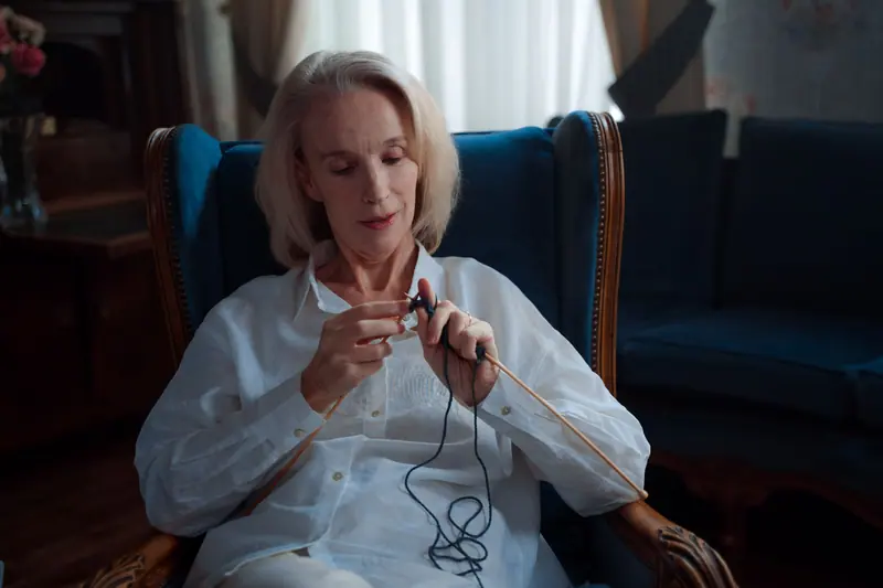 A resident knitting in a blue wingback chair