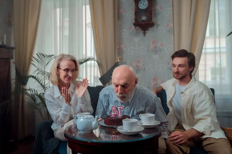 A resident blowing out the candles on his birthday cake with family